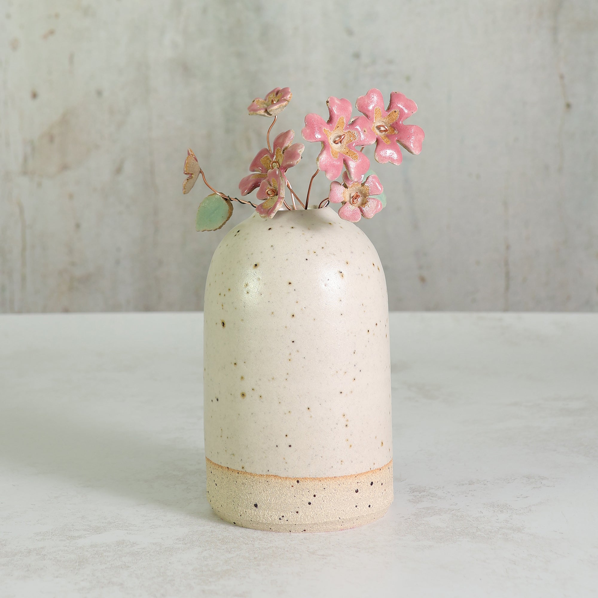 Speckled british made ceramic vase with stoneware pink flowers on a light background
