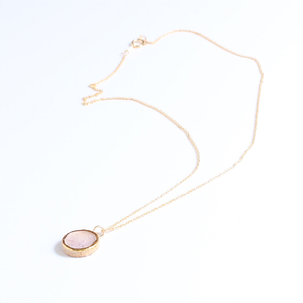 Necklace with a pink round pendant on a white background