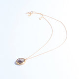 Gold necklace with a purple pendant on a white background