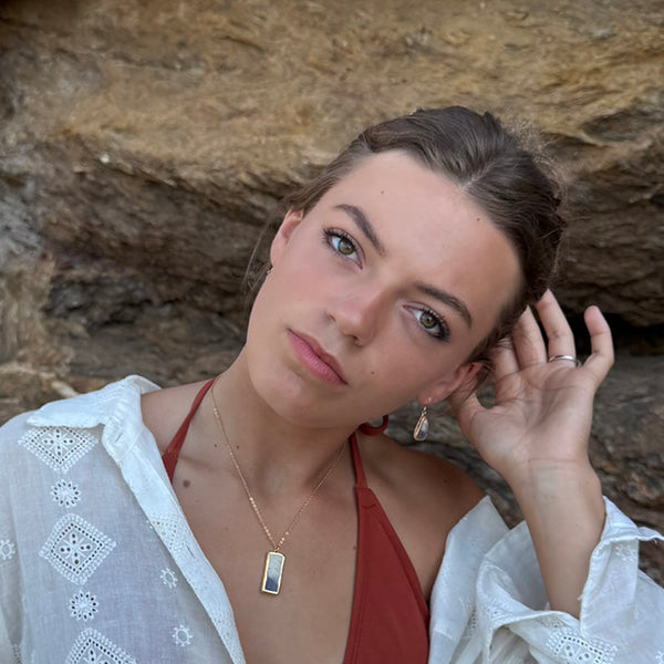 Woman posing whilst wearing handmade elements inspired jewellery against a rocky background