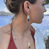 Woman wearing a necklace and earrings with a scenic background