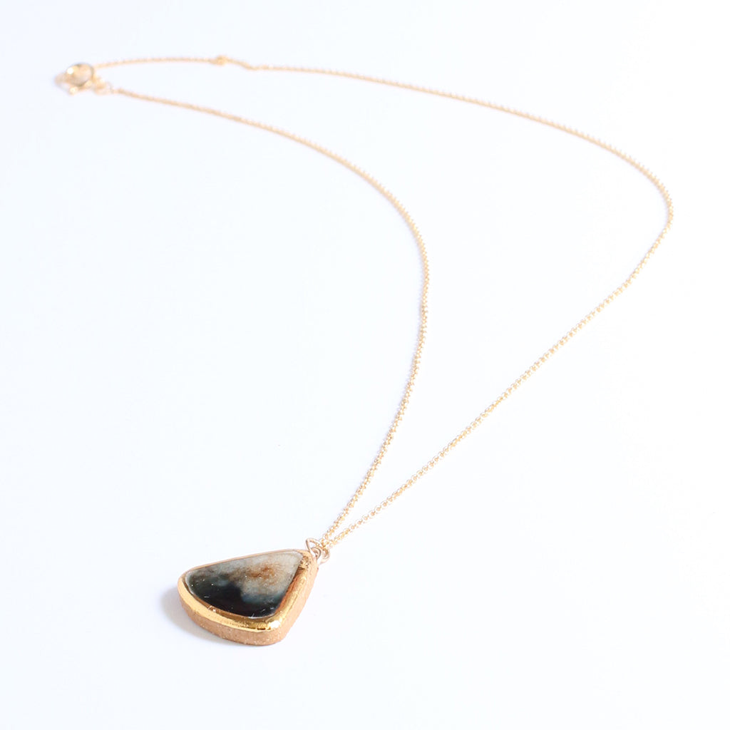 Necklace with a gold chain and a triangular pendant on a white background