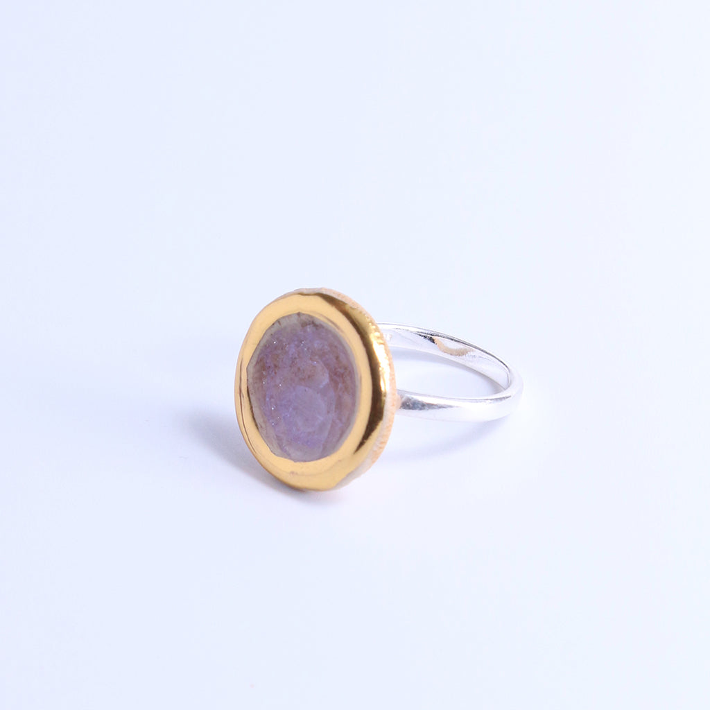 Pink ring with gold and silver design on a light grey background