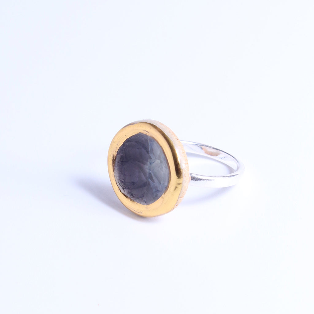 Silver ring band with a ceramic and glass charm in size large. The charm features smoky-purple coloured glass and gold lustre detailing around its outer edge.  