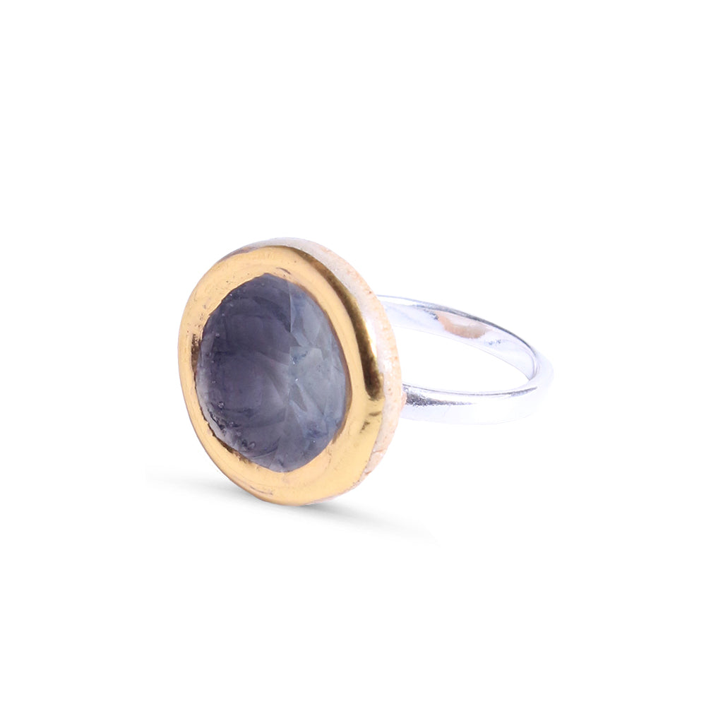 Ring with gold bezel and purple stone on a white background
