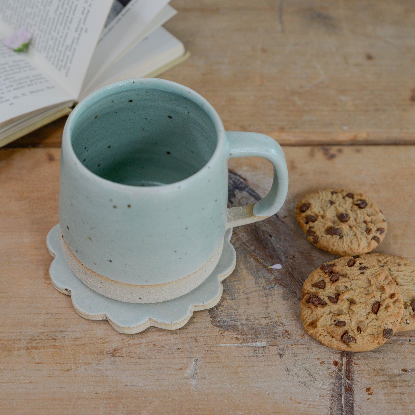 Mint green mug on a mint green flower coaster with cookies