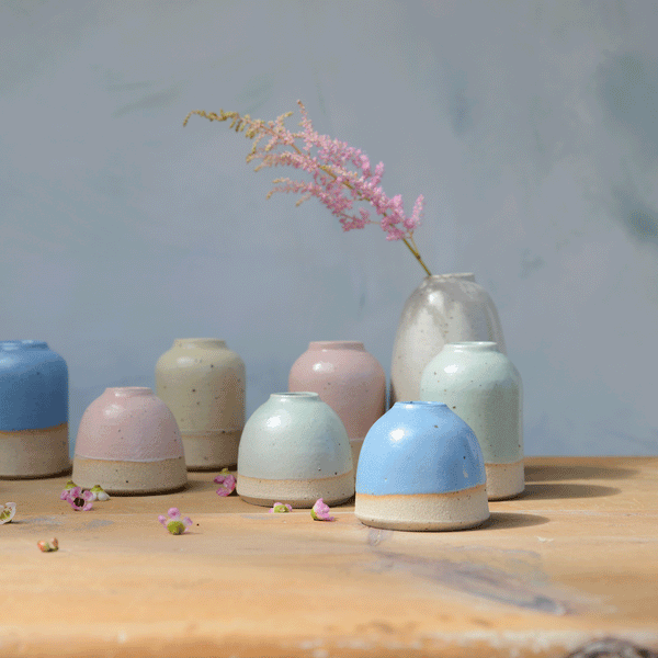 Collection of different sized pastel vases in the sunlight with blue mini vase at the front