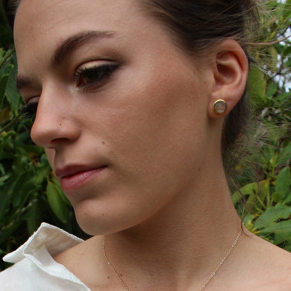 Close-up of a woman wearing earrings with a green leafy background