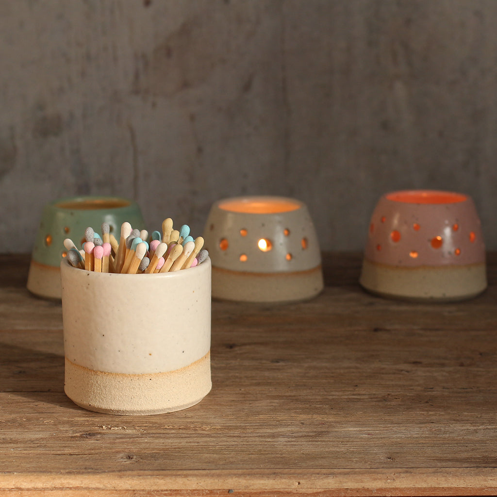 White match pot with pastel matches in front of 3 lit pastel tealights