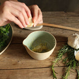 Garlic cloves being peeled and ready to be pureed in green bowl