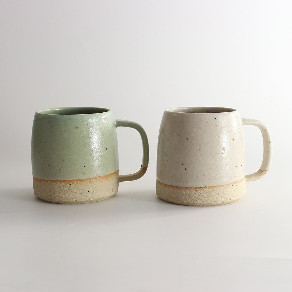 Plain glazed back of mint green and off-white mugs