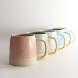 Row of five pastel stoneware mugs