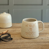 Handmade Stoneware personalised handwriting mug with 'Arwen Loves Daddy' on the front. The mug sits on a wooden table next to a matching ceramic suagr pot, a copper spoon and black-rimmed glasses nearby.