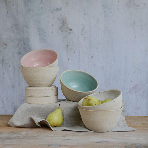 Stoneware cereal bowls displayed at different levels and angles with pears