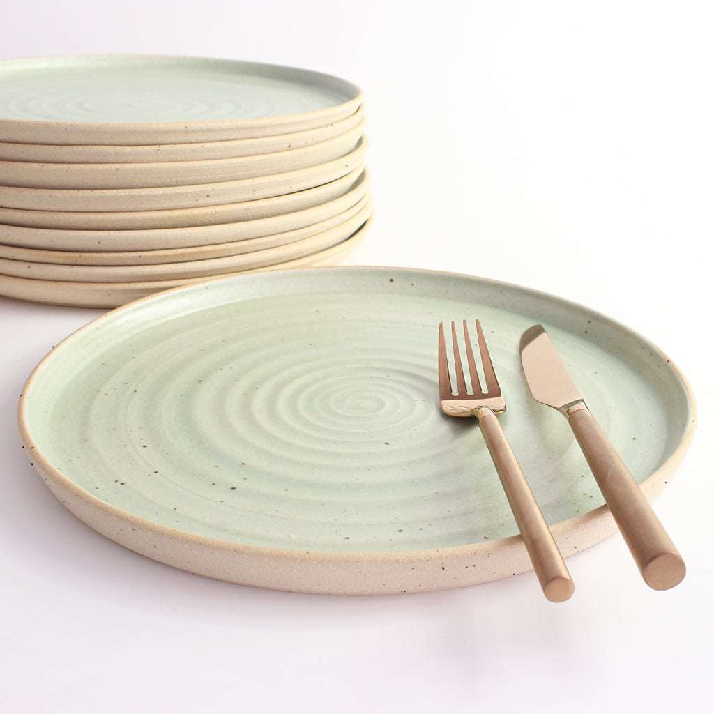 Mint Green dinner plate with copper cutlery next to stack of plates