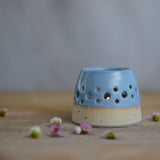Close up of blue glaze and flecked stoneware of lit tealight
