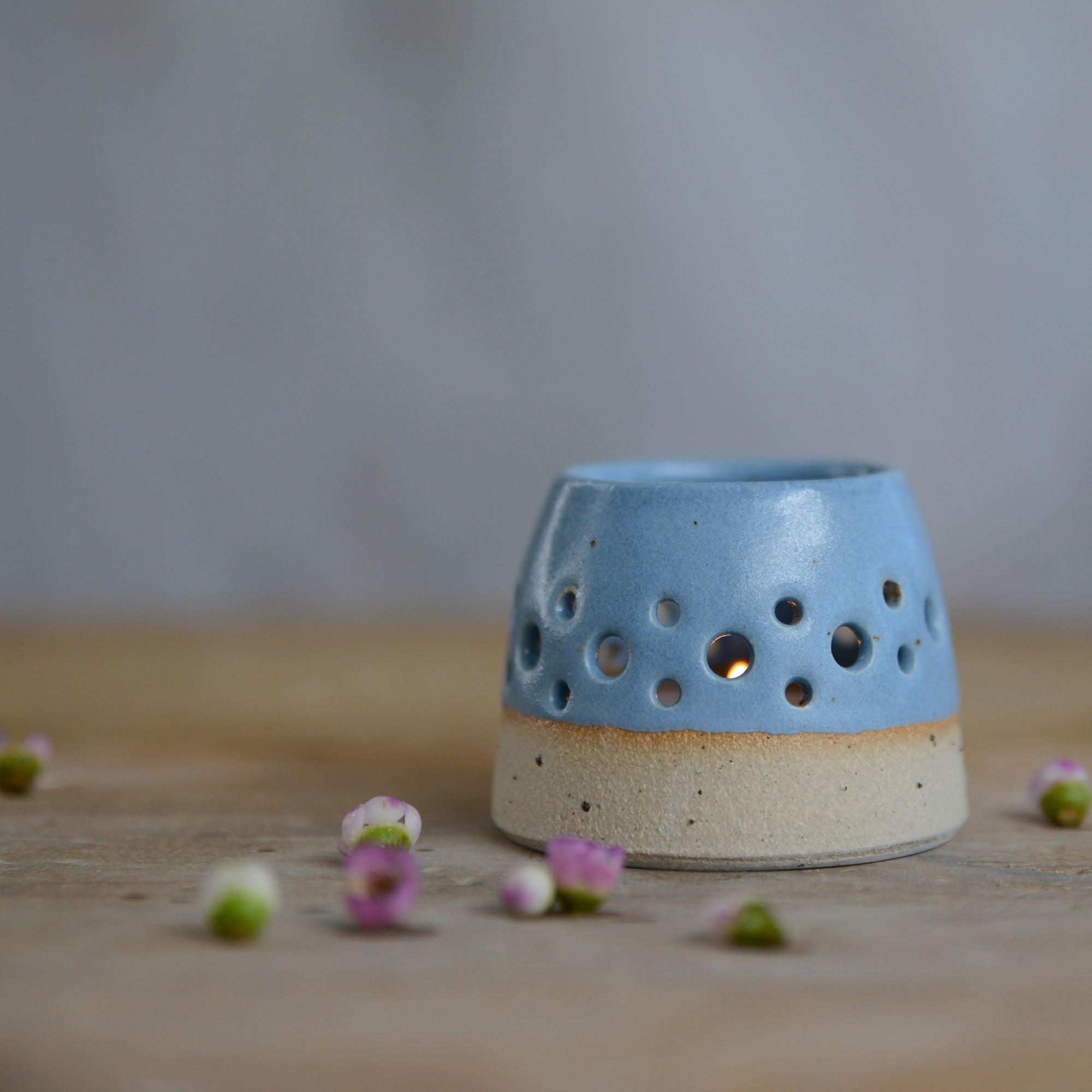 Close up of blue glaze and flecked stoneware of lit tealight