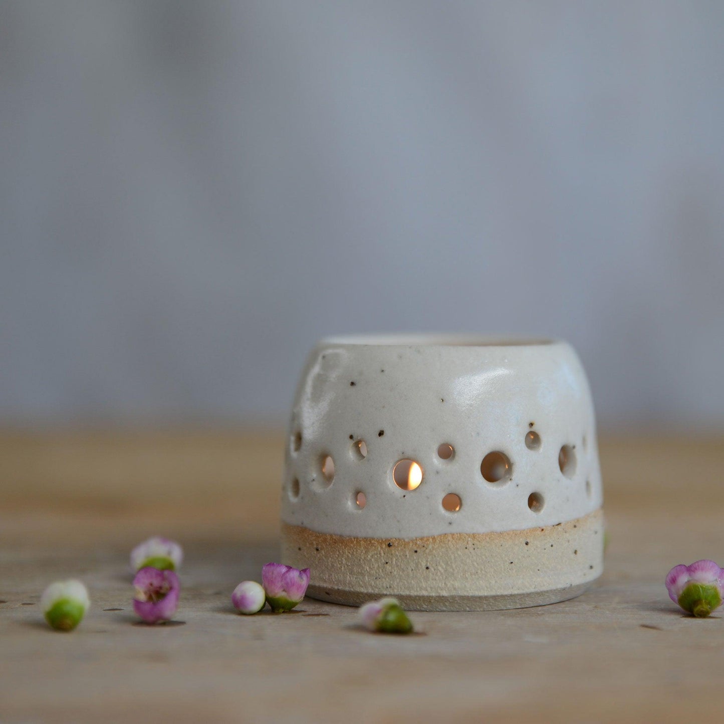 Close up of flecked stoneware and white glaze on lit tealight