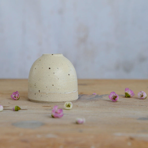 Close up of flecked stoneware and yellow glaze on mini vase