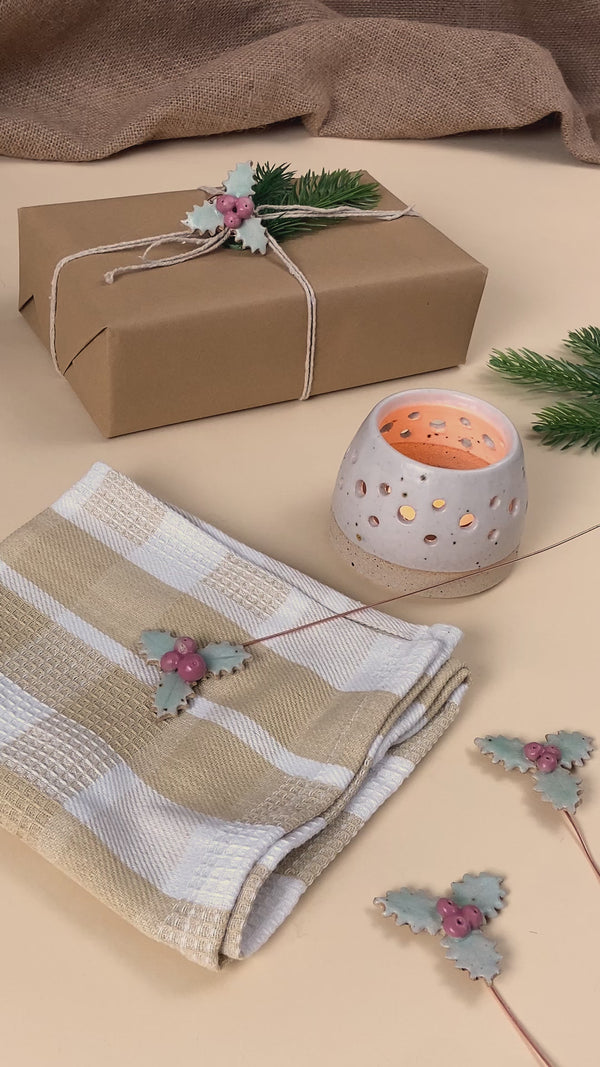 Video showing ceramic holly decoration with multiple uses, such as a christmas napkin ring and gift wrap decoration 