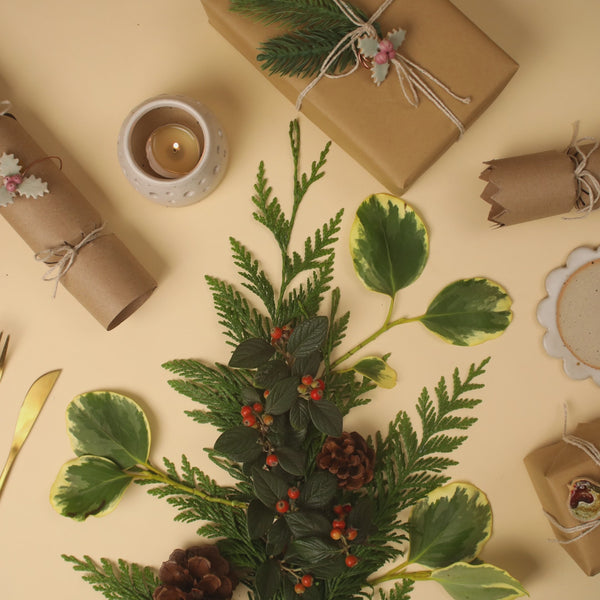 Stop motion video showing a ceramic snowman, robin and penguin landing on green foliage surrounded by a ceramic tealight and presents and christams crackers wrapped with ceramic holly decorations 