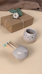 Video showing a ceramic bird matchpot which contains matches with a striking pad on the bottom of the bird. One of the matches is lit on the pad and used to light a tealight in a ceramic tealight holder. 