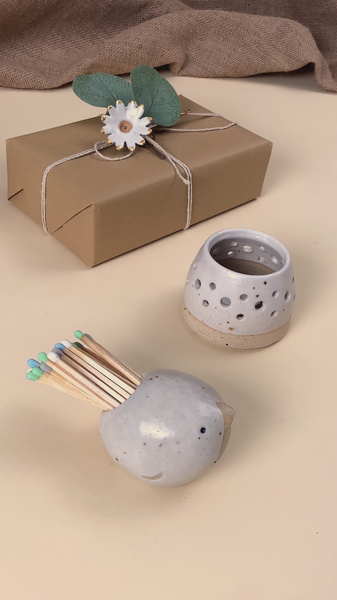 Video showing a ceramic bird matchpot which contains matches with a striking pad on the bottom of the bird. One of the matches is lit on the pad and used to light a tealight in a ceramic tealight holder. 
