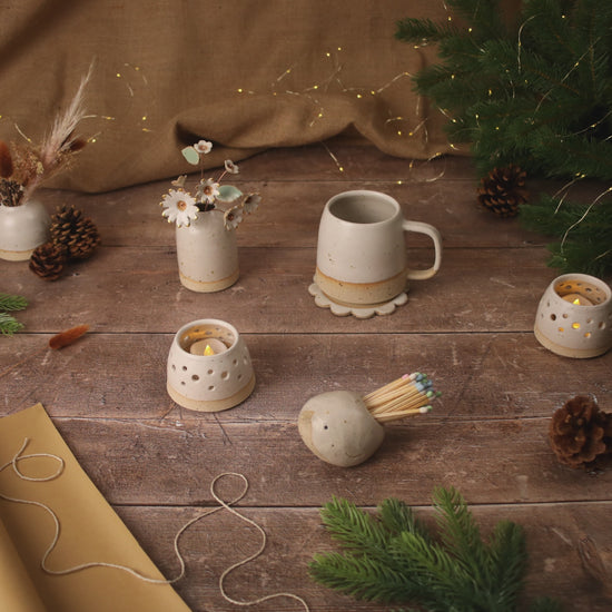 stop motion video of handmade ceramics, a mug, tealight, coaster, bird match striker pot spin and then transition into wrapped Christmas presents 