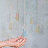 All 5 pastel light pulls hanging with the front blue one being held for size reference