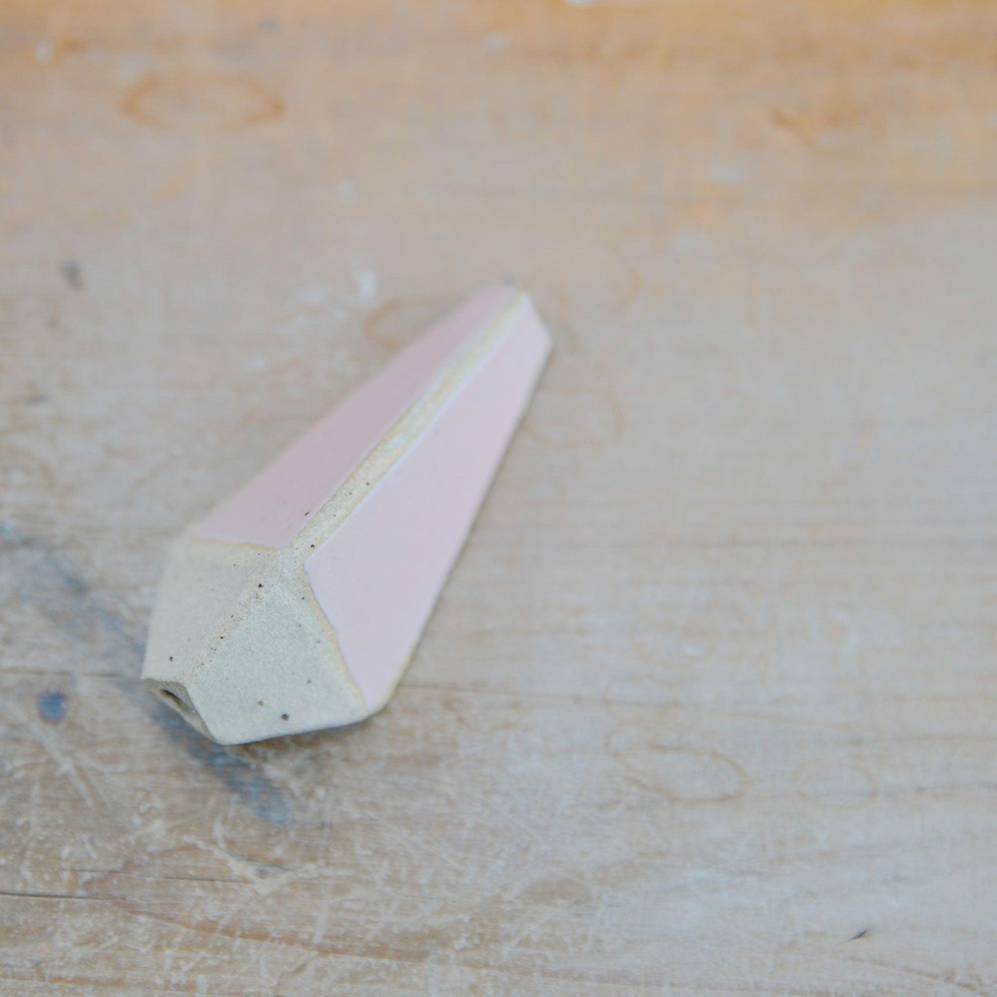 Close up of flecked stoneware and pink glaze on light pull handle