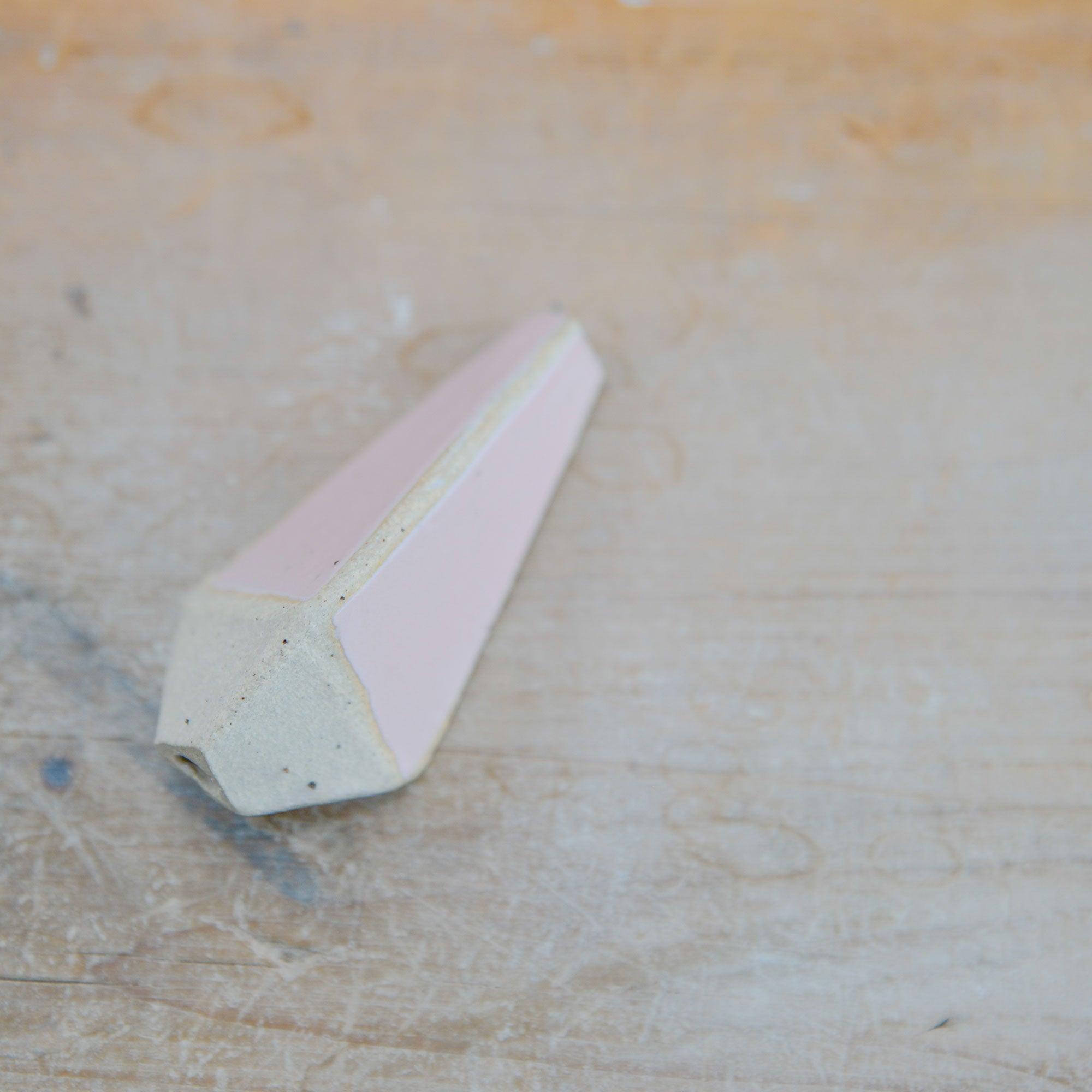 Close up of flecked stoneware and pink glaze on light pull handle