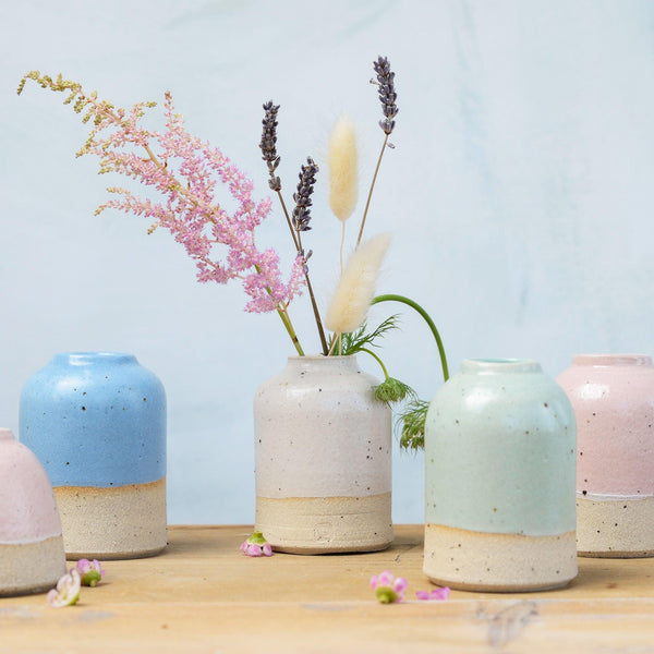 Small pastel vases with white vase in centre full of wilflowers