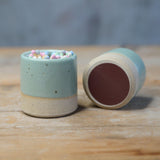 2 green match pots, one on its side showing the underside striker pad