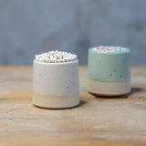White match pot with white matches in front of mint match pot with pastel matches