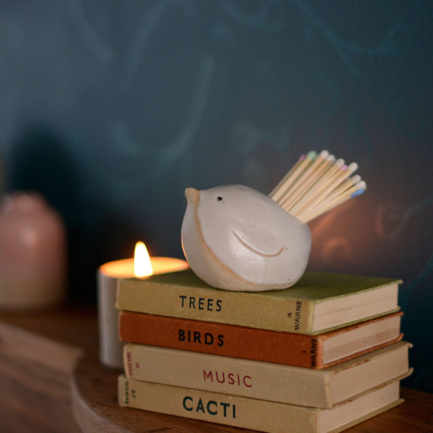White bird pot on top of old stack of books on mantlepiece