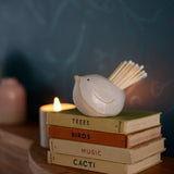 White bird pot on top of old stack of books on mantlepiece