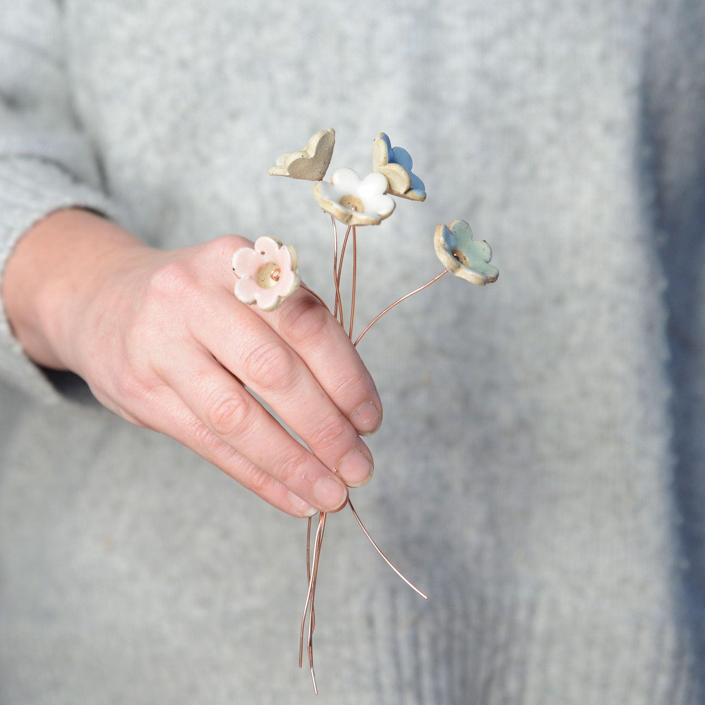 Hand holding all 5 pastel ceramic flowers