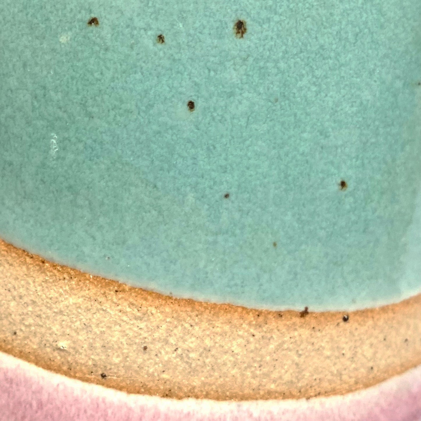 Close up of natural clay flecks coming through the blue and pink glazes