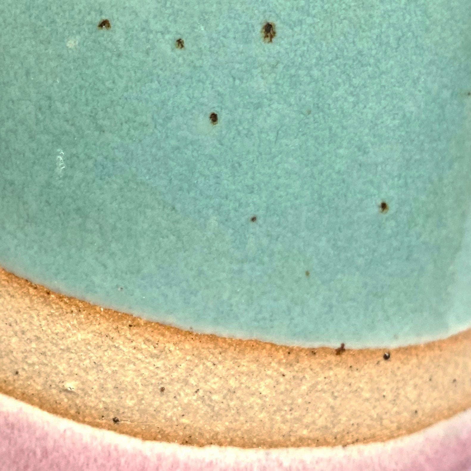 Close up of natural clay flecks coming through the blue and pink glazes