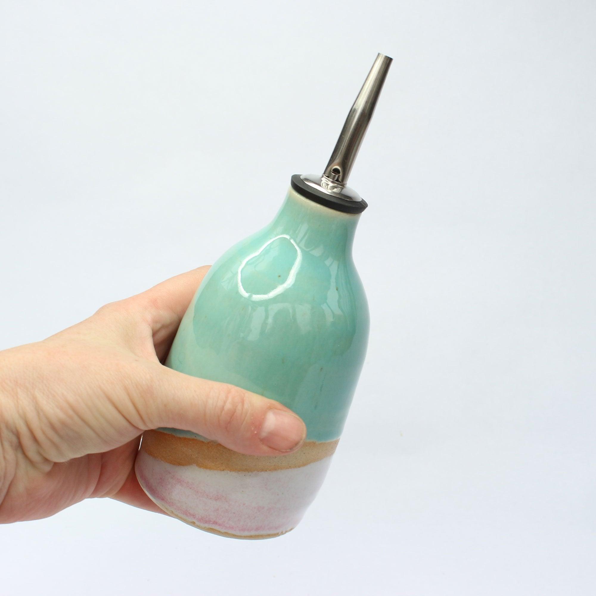 A hand holding the oil pourer for size reference