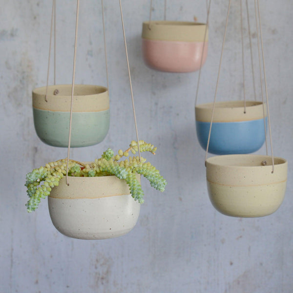 All planters hanging from different levels with white planter at front