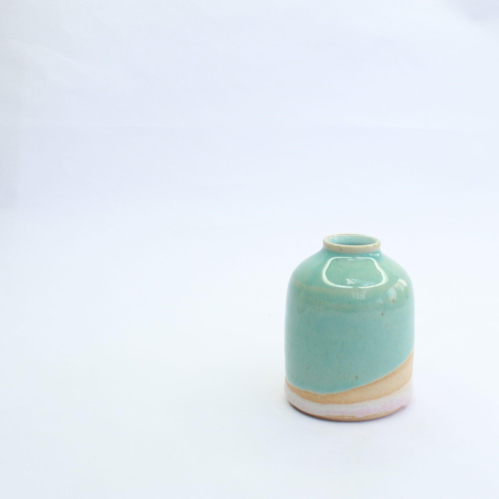 Alternative side view of the glossy turquoise glaze in the light on the mini vase