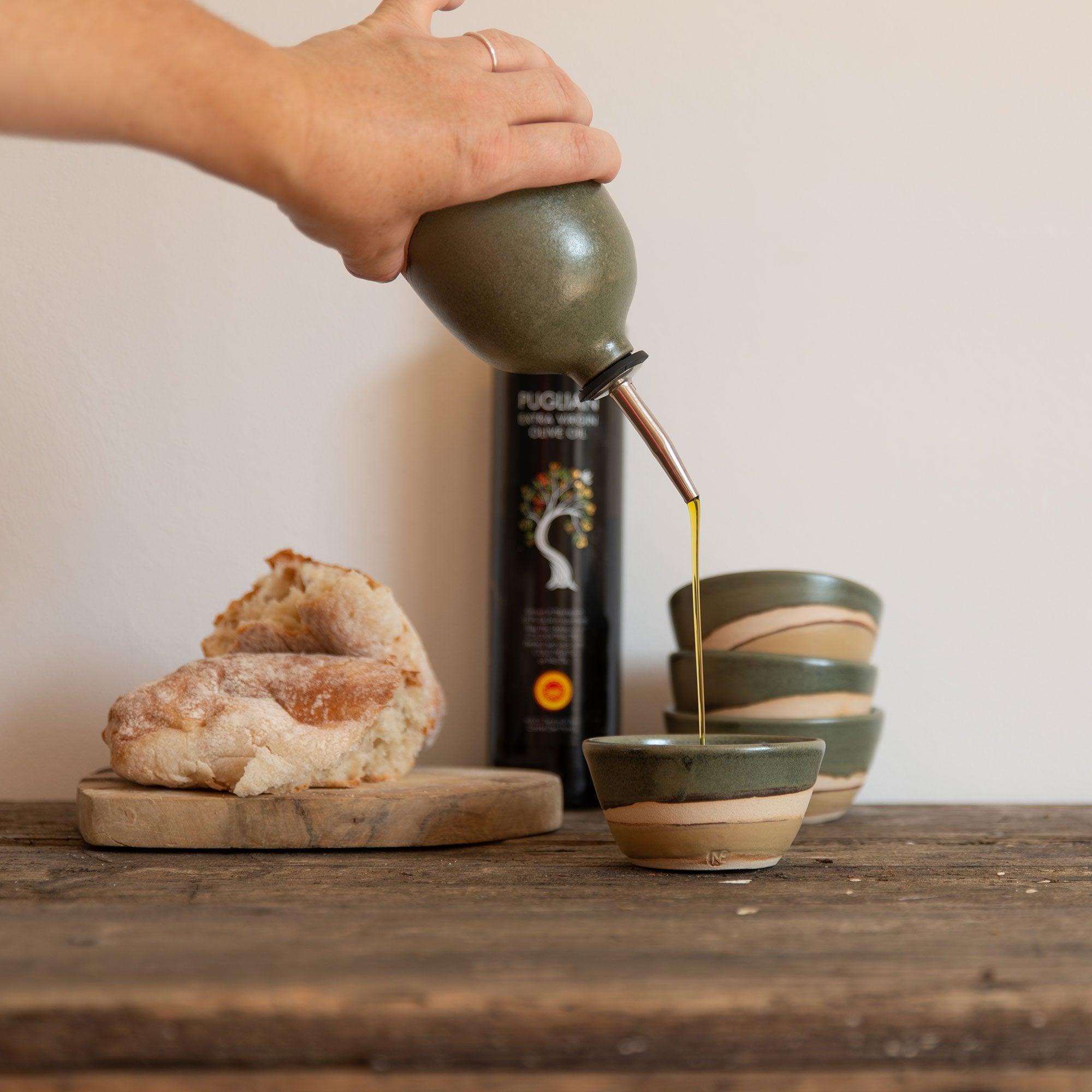 Oil being poured from the pourer into a matching mini bowl for dipping bread in