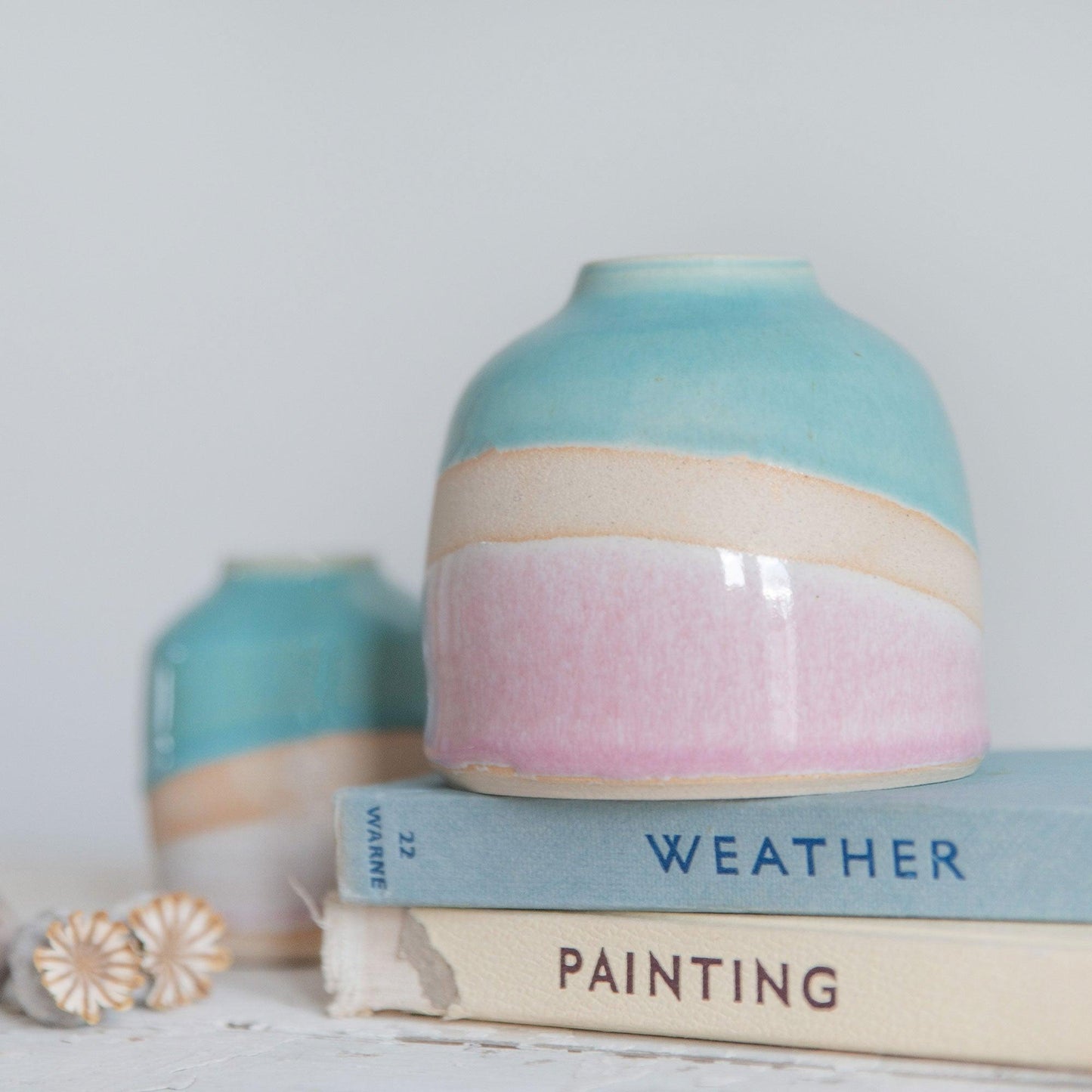 Close up of the pink glaze showin the pale to darker pink gradient against the exposed clay with a rim of orange burnoff. A mini Shoreline vase sits in the background