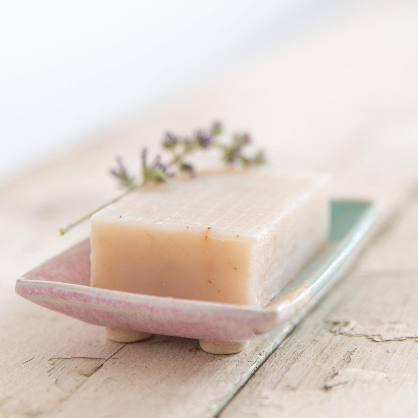 Close up end view of soap bar and soap dish glazed pink edges and clay feet on the base