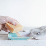 A hand taking soap out of the shoreline soap dish to show size