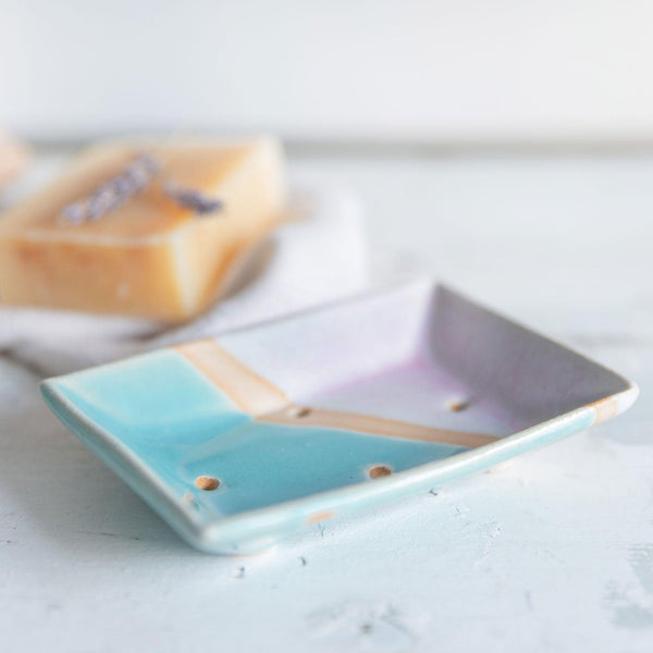 Close up side view of the four drainage holes and shiny turquoise glaze of the soap dish