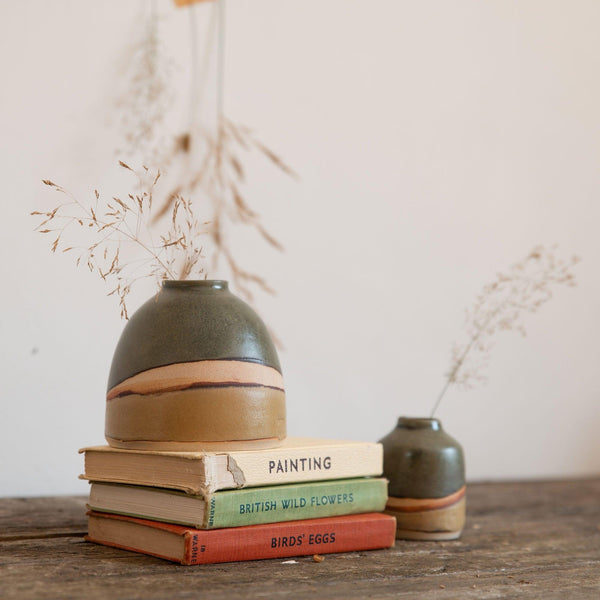 Close up of the dome vase on the stack of vintage books showing the green and brown satin glaze