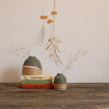 Moorland dome vase on stack of vintage books with a mini moorland vase to the right. Both vases have dried seed stems in, with similar dried stems taped to the wall behind.
